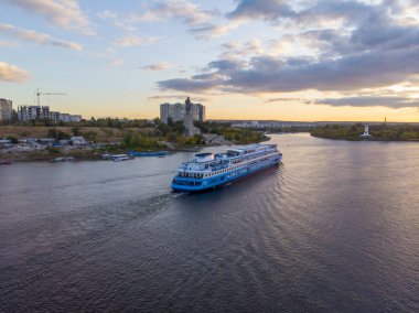 Seyahat. İçinde turistler olan büyük mavi-beyaz bir yolcu gemisi.
