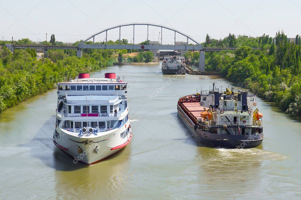 A cruise ship with tourists passes through the Volga-Don Shipping Canal named after Lenin and diverges from cargo ships. Volgograd. Russia/              