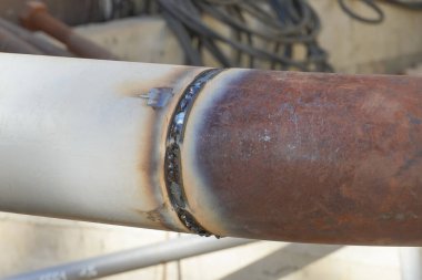 Undercooked weld butt covered with slag. Piping during manual arc welding using an electrode. Installation and welding of industrial pipelines and equipment.                  
