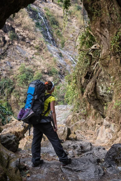 Menina com mochila assistindo a uma cachoeira Fotos De Bancos De Imagens