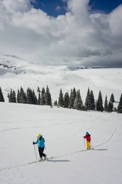 A couple of skiers following a track in the snow — Stock Photo, Image