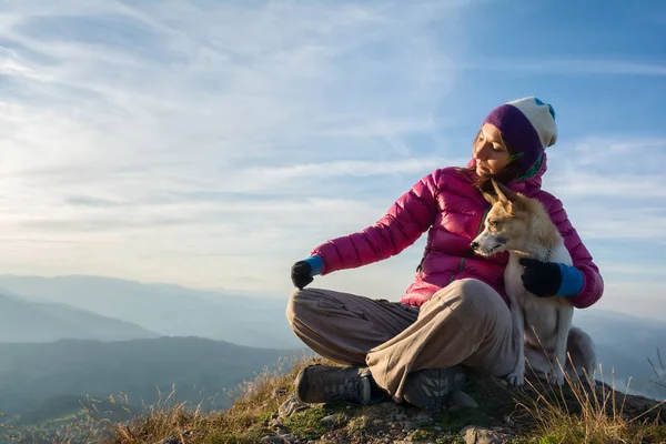 Flicka och hennes hund tillsammans på en topp Stockbild