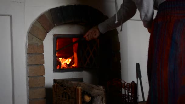 Girl arranging the wood in the fireplace and closing the metal door after wards. Close-up, the action is happening in a mountain cabin. — Stock Video