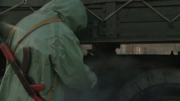 Солдат в комбинезоне дезинфицирует грузовик — стоковое видео