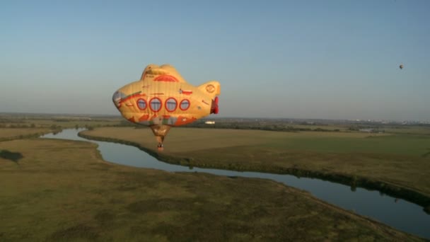 Funny hot air balloon flies above ground — ストック動画