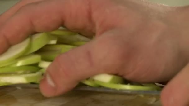Повар, нарезающий свежее зеленое яблоко на плите — стоковое видео