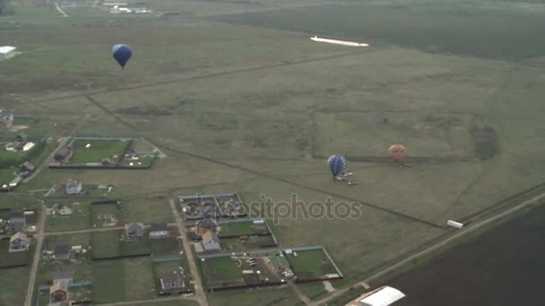 Hot air balloon aerial view on field and cottages — Stock Video