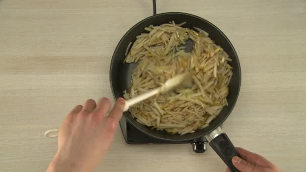 Un homme brassant des poires coupées dans une poêle — Video