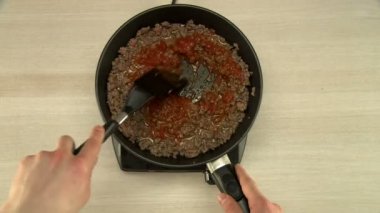 Pişirme sırasında fasulye ve eti karıştırır.