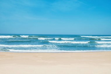 Sandy beach ve dalgalı dalgalar. Beyaz kum, mavi gökyüzü ve kristal denizin tropikal Beach