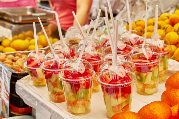 Нарезанный мандарин, клубника, киви и дыня в стакане на рынке уличной еды
