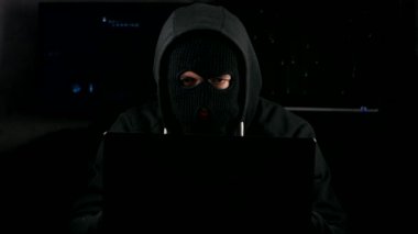 Tehlikeli hacker bir karanlık office odada bir bilgisayarda çalışan bir maske'ı