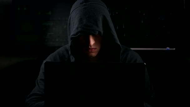 Mysterieuze hacker in een mantel die werken op een computer in een donkere kantoorruimte — Stockvideo