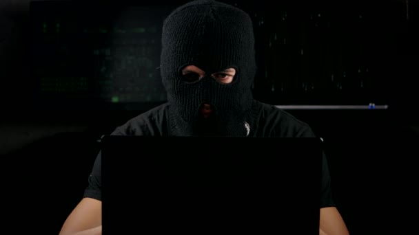 Farliga hacker i en mask som fungerar på en dator i en mörk kontorsrum — Stockvideo