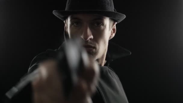 Gangster in a hat and a black cloak. Mafioso aiming a gun at the camera — Stock Video