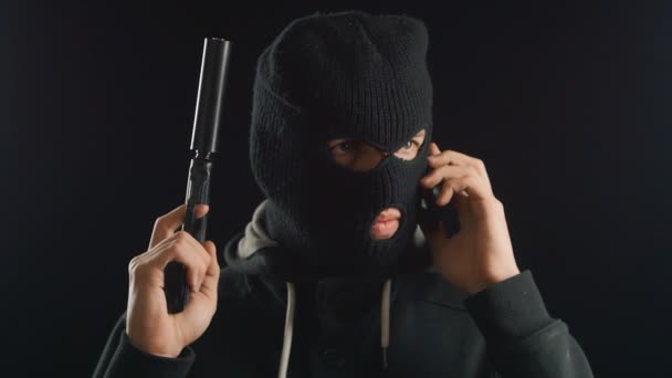 Опасный террорист в балаклаве разговаривает по телефону. требование выкупа . — стоковое видео