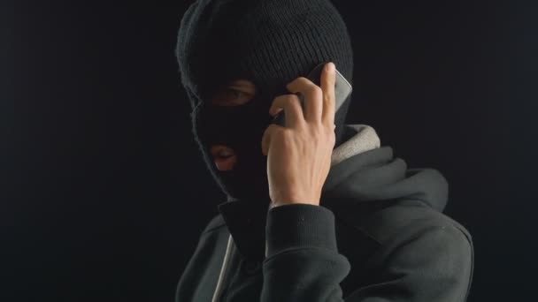 Dangerous terrorist in balaclava talking on the phone. redemption requirement. — Stock Video