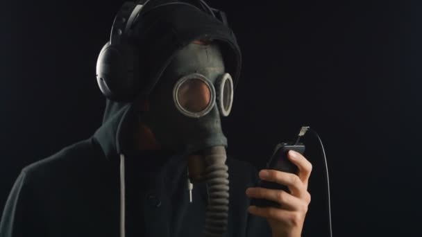 homme écoute de la musique avec un casque avec un masque à gaz couvrant son visage .
