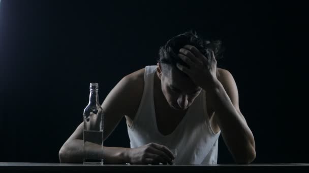 Depressed man drinking vodka in a dark room. man in despair — ストック動画