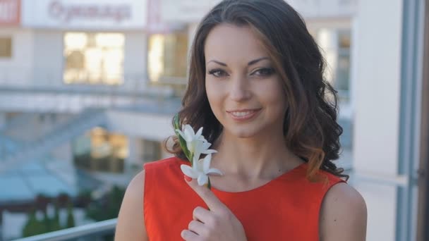 Primer plano de bonita morena en un vestido rojo con una flor en la mano — Vídeos de Stock