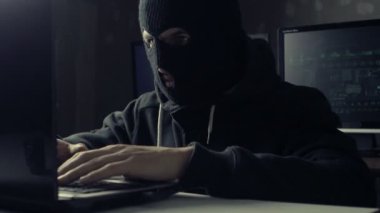 Tehlikeli hacker bir karanlık office odada bir bilgisayarda çalışan bir maske'ı