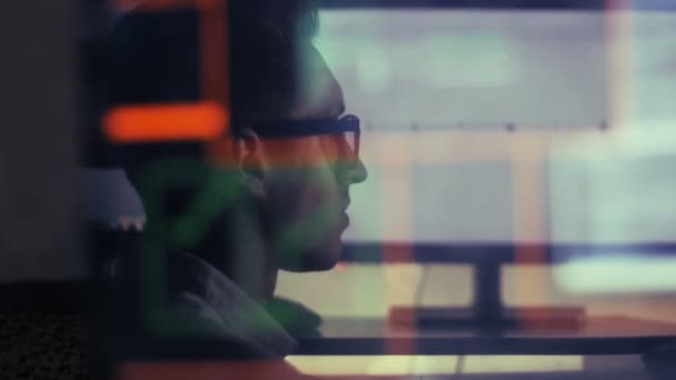 Man aan het werk op een laptop in de reflectie van de monitor — Stockvideo
