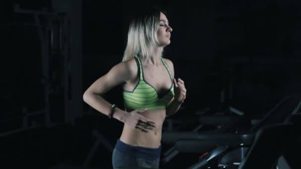 Atractiva chica caucásica corriendo en una cinta de correr en el gimnasio deportivo en cámara lenta — Vídeo de stock
