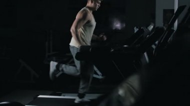 Slowmotion içinde spor salonunda bir koşu bandı üzerinde çalışan adam