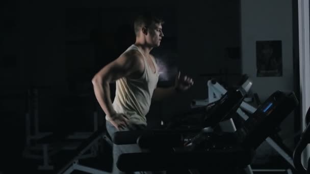 Чоловік біжить на біговій доріжці в спортивному тренажерному залі в уповільненому режимі — стокове відео