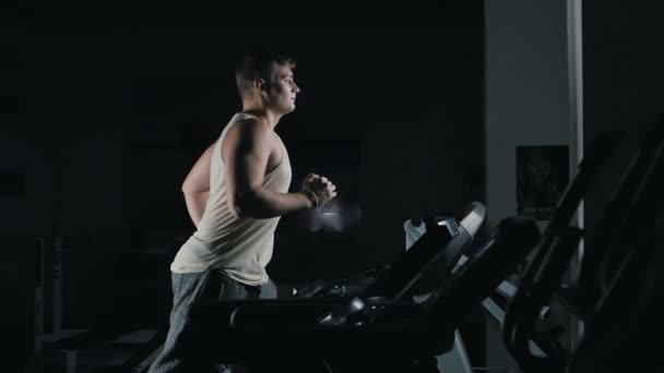 Slowmotion içinde spor salonunda bir koşu bandı üzerinde çalışan adam — Stok video