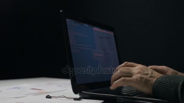 Hombre mayor trabajando en un portátil en habitación oscura — Vídeos de Stock