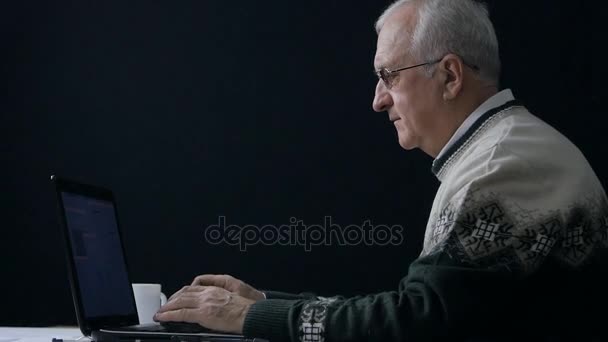 暗い部屋でラップトップで働く年配の男性 — ストック動画