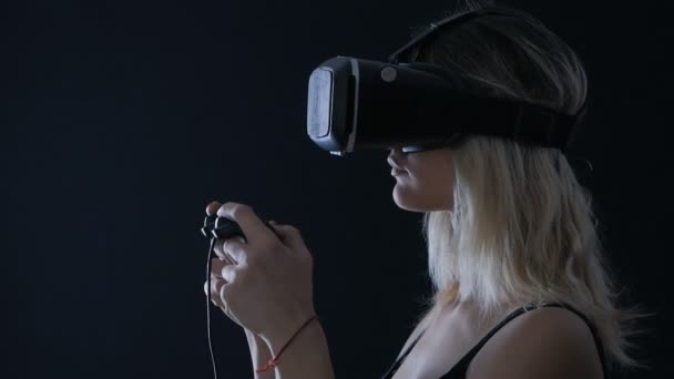 Virtual reality game. Girl with pleasure uses head-mounted display in dark room — Stock Video