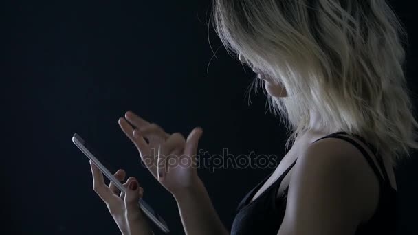 Hezká dívka pracuje na digitálním tabletu v temné místnosti — Stock video