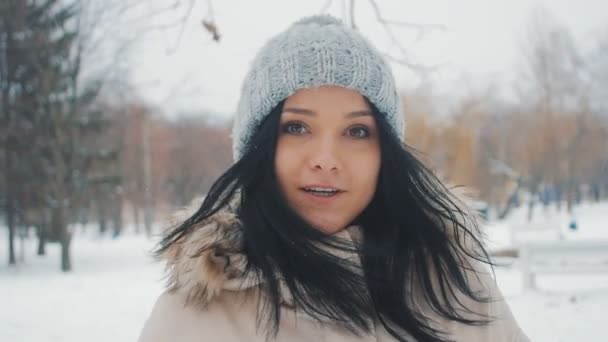 Молодая симпатичная девушка в шляпе в зимнем парке. она смеется и дурачится вокруг — стоковое видео