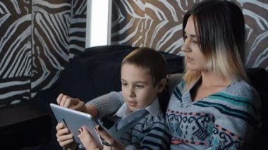 Neşeli küçük çocuk ve annesi dijital tablet kullanma kanepede oturan