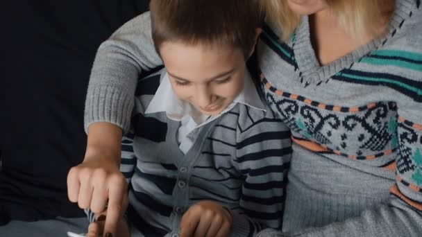 Vrolijk jongetje en zijn moeder zitten op de Bank met behulp van een digitaal tablet — Stockvideo
