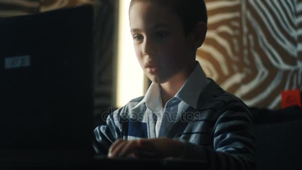 Μικρό αγόρι παίζοντας παιχνίδια στον υπολογιστή σε ένα φορητό υπολογιστή στο σπίτι — Αρχείο Βίντεο