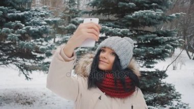 Selfie onun smartphone ile yapıyor genç sevimli kız kış Park