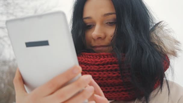 Молодая симпатичная девушка в зимнем парке пользуется планшетным компьютером — стоковое видео