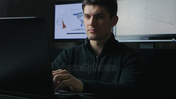 Młody inżynier haker człowiek pracuje na komputerze przenośnym w ciemnym pokoju — Wideo stockowe