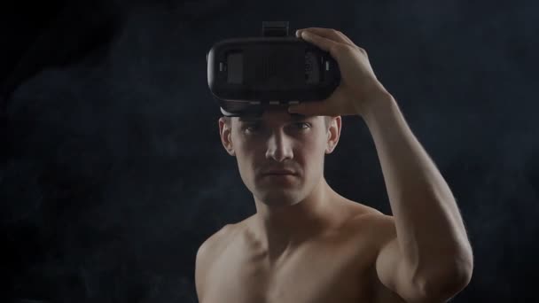Hombre consiguiendo experiencia usando VR-auriculares, de pie en la oscuridad, con humo a su alrededor . — Vídeos de Stock