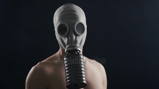 Homem com máscara de gás em pé no escuro, com fumaça ao seu redor . — Vídeo de Stock