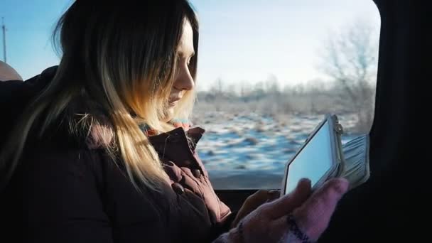 Mujer joven viajando en coche en un día soleado. Ella usando tableta pc — Vídeo de stock