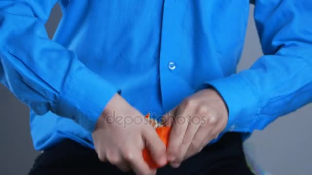 Boy cleans tangerine at home — Stock Video