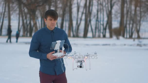Un hombre controla un dron en el jardín de invierno — Vídeo de stock