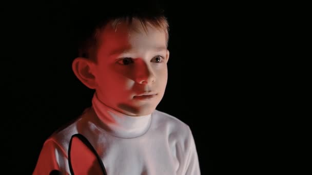 Ragazzo che guarda cartoni animati, a volte bambino che sembra spaventato. Illuminazione low-key del viso dei bambini — Video Stock