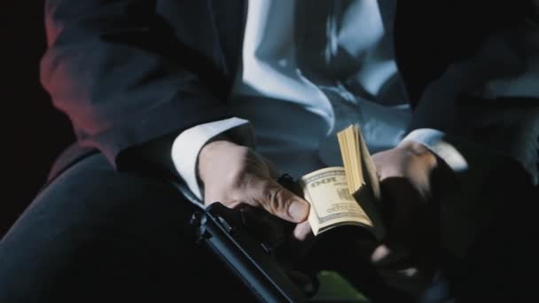 Närbild händerna på en farlig man med en pistol räknar pengar. Smutsiga pengar Mafia. — Stockvideo