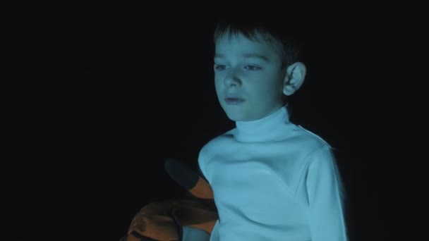 Jeune garçon regardant des dessins animés dans une grande pièce sombre — Video