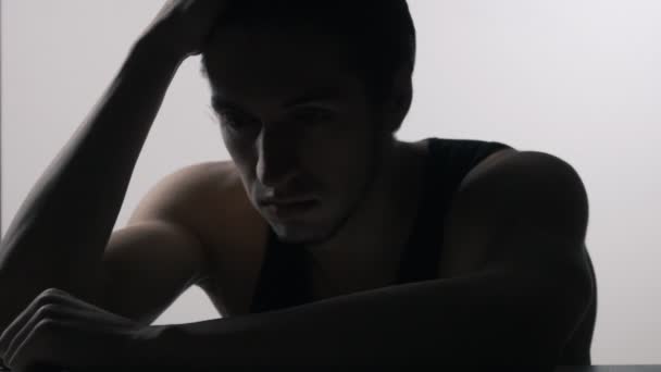 Masada oturan depresif, üzgün genç adam silüeti — Stok video